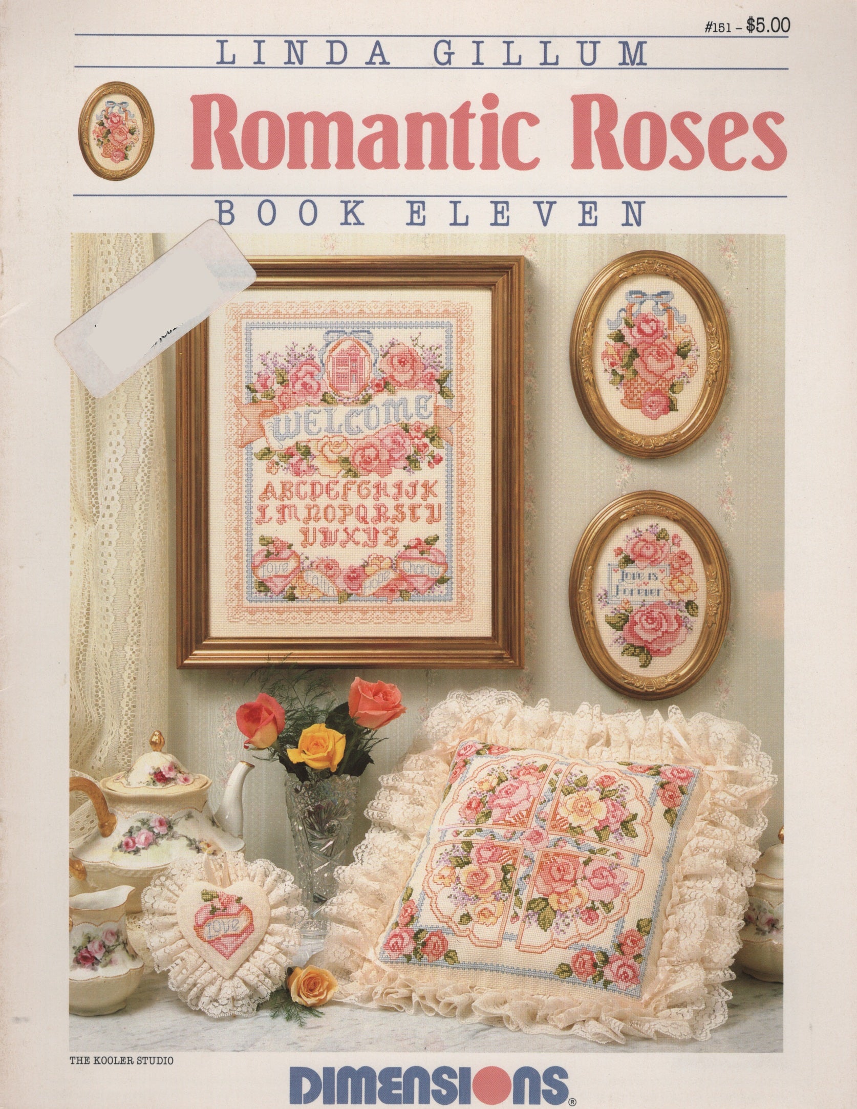 Front cover of Linda Gillum's 'Romantic Roses Book Eleven' cross stitch pattern by Dimensions, featuring a vintage-style collage of embroidered rose-themed needlework and floral home decor on an off-white background. 151