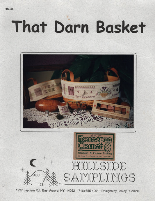 Front cover of a needlework sampler cross stitch pattern titled "That Darn Basket" from Hillside Samplings, showing a decorated basket and sampler items HS-34